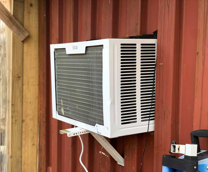 A wall AC unit helps convert an old shipping container into an on-site refrigeration system.